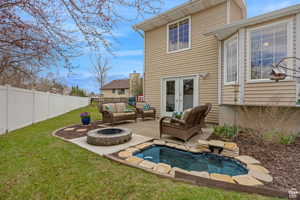 Rear view of property featuring an outdoor living space with a fire pit, a fenced in pool, a lawn, and a patio area