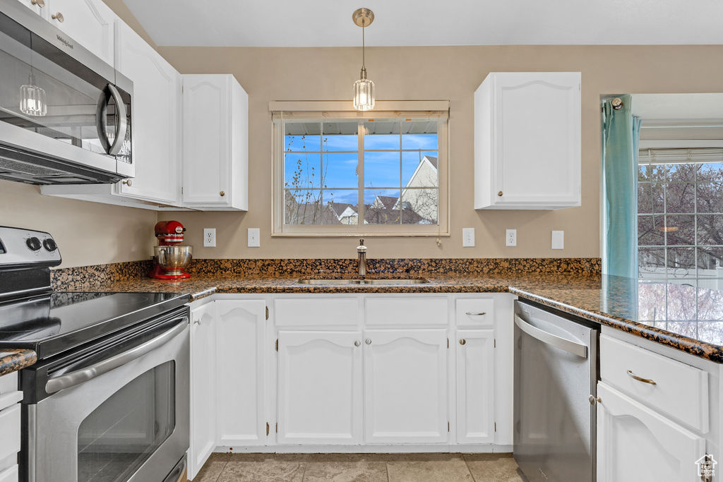 Kitchen with white cabinets, plenty of natural light, stainless steel appliances, and sink