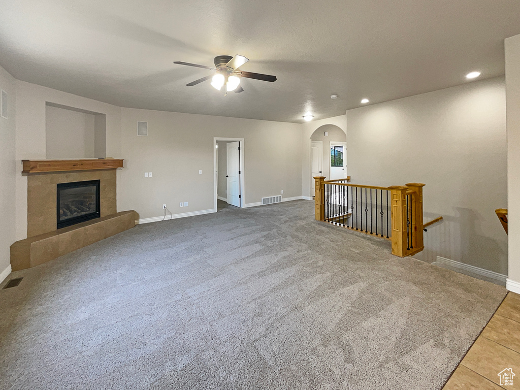 Unfurnished living room with a ceiling fan, arched walkways, a fireplace, recessed lighting, and tile patterned flooring
