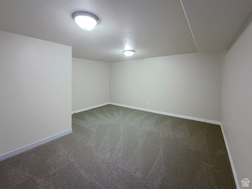 Spare room featuring dark carpet and a textured ceiling