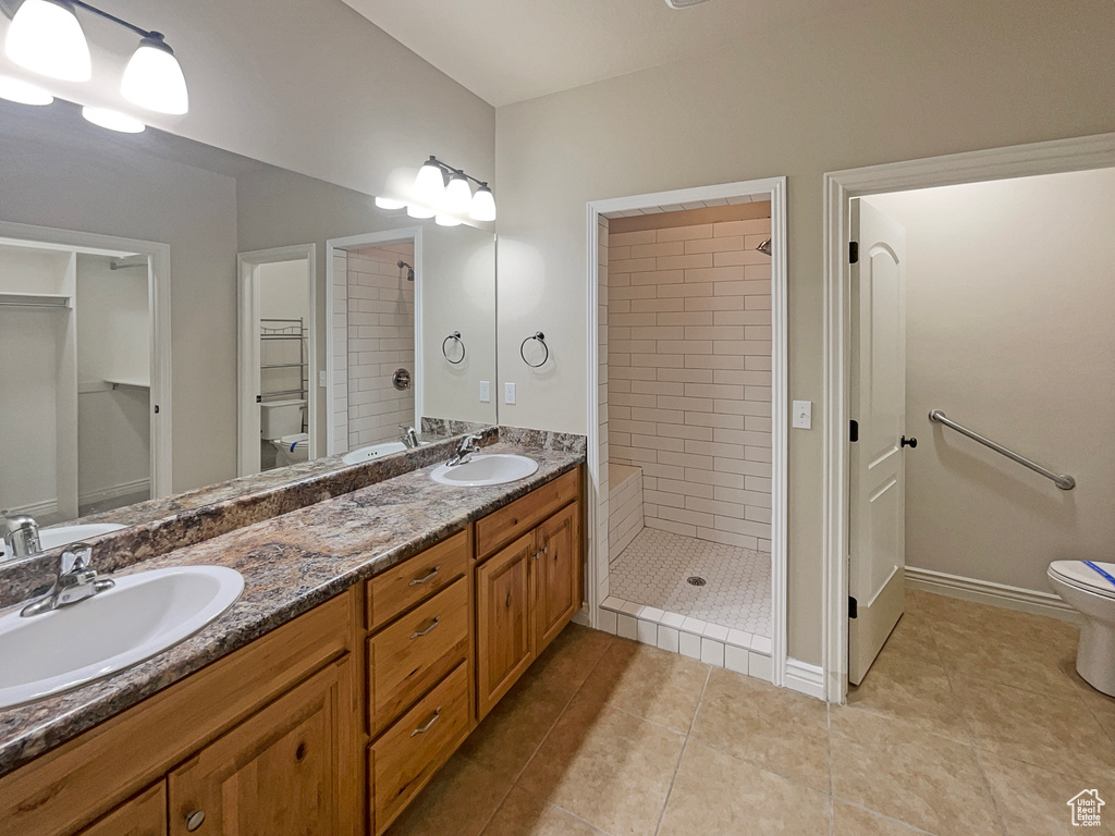 Full bathroom with double vanity, a shower stall, tile patterned floors, and a spacious closet