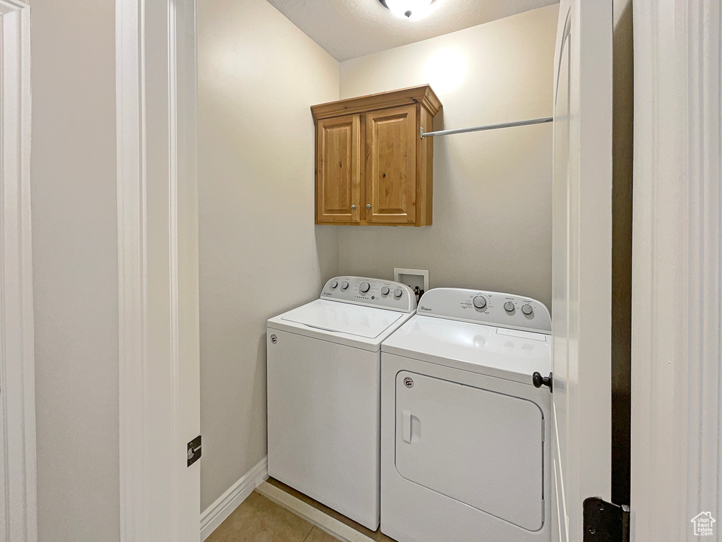 Laundry room with cabinet space, washing machine and dryer, and light tile patterned floors