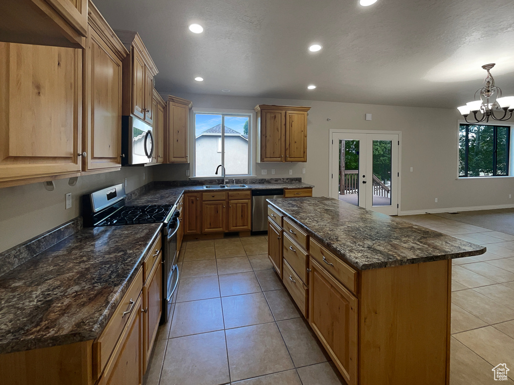 Kitchen with stainless steel appliances, healthy amount of natural light, a kitchen island, recessed lighting, and light tile patterned floors