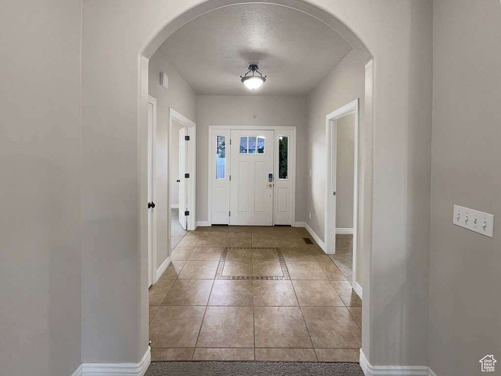Tiled entrance foyer with arched walkways and baseboards