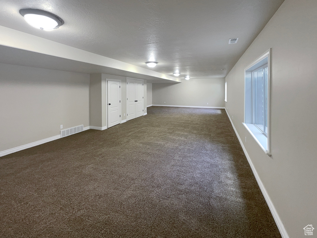 Below grade area with dark carpet and baseboards