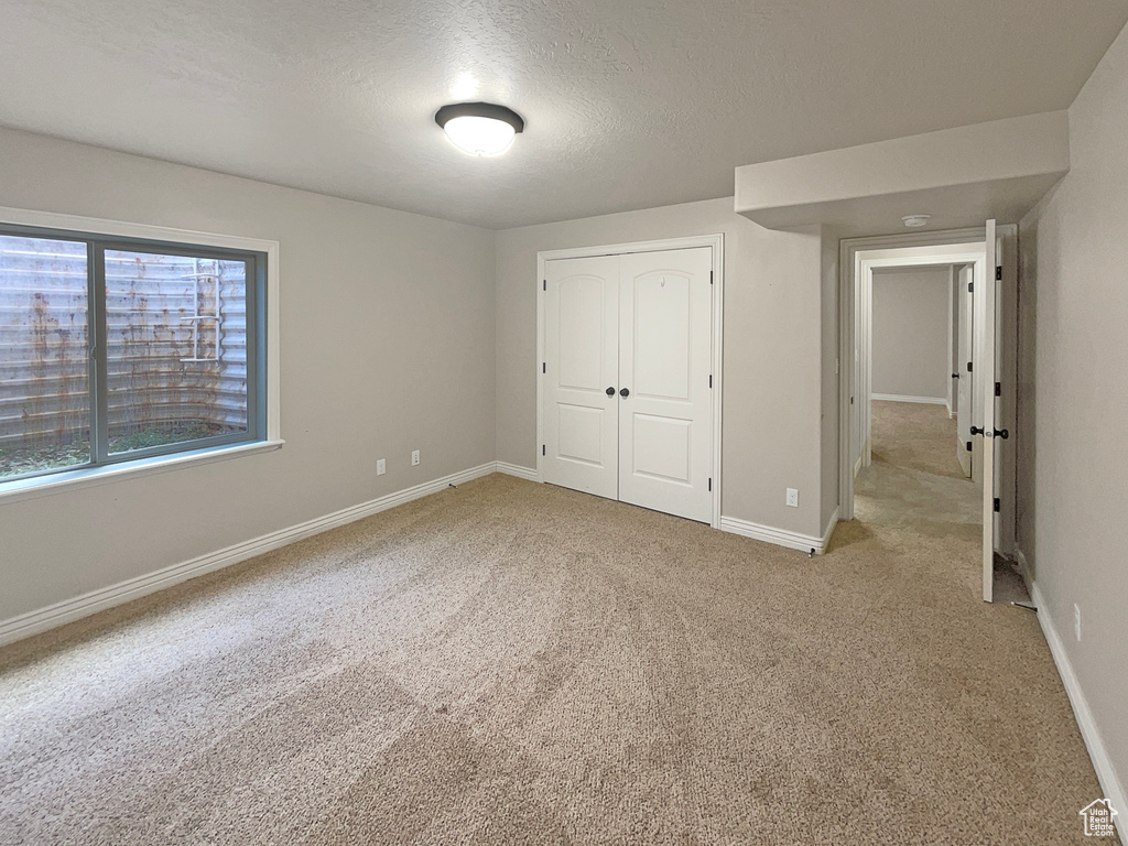 Unfurnished bedroom featuring light colored carpet, a closet, and a textured ceiling