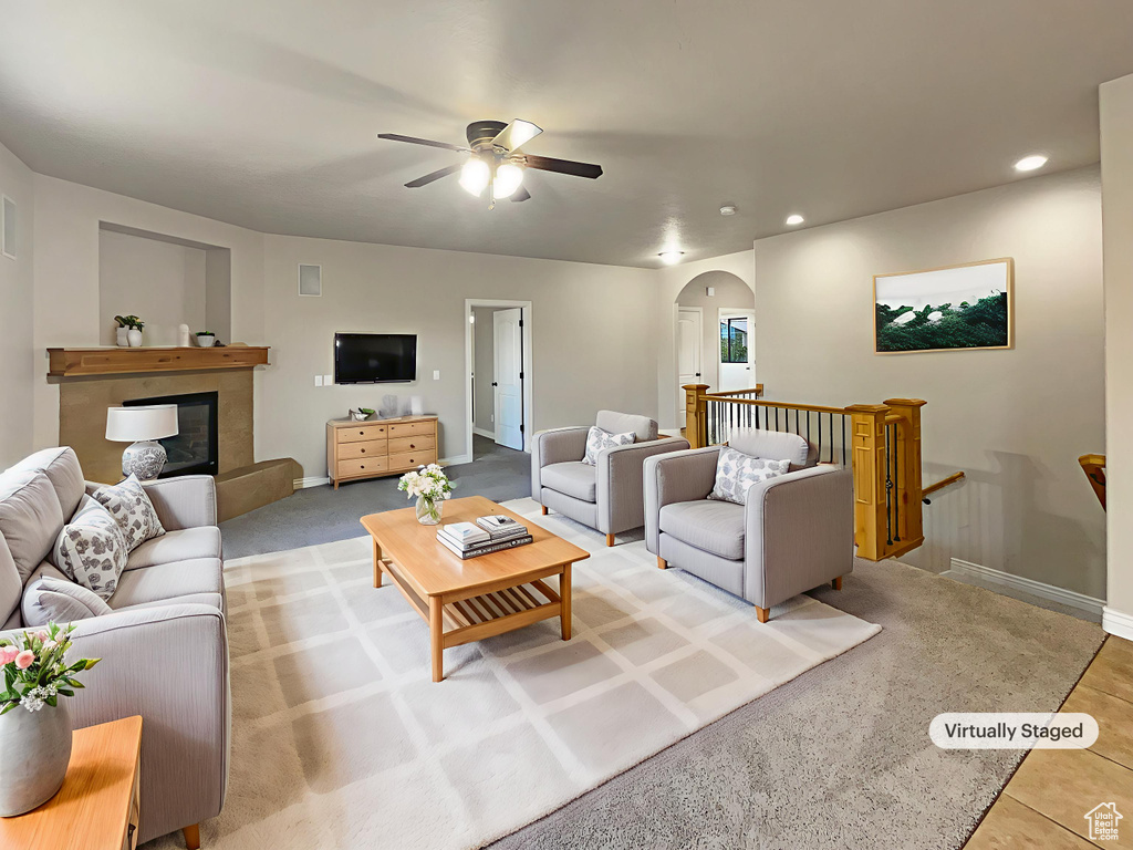 Living area featuring arched walkways, ceiling fan, recessed lighting, and a glass covered fireplace