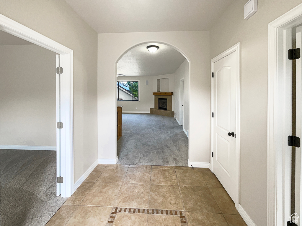 Hallway featuring carpet flooring, arched walkways, and tile patterned flooring