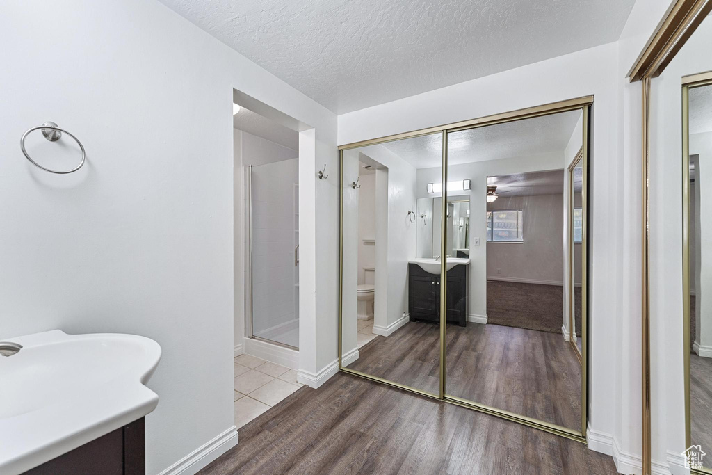 Bathroom featuring toilet, vanity, hardwood / wood-style floors, a textured ceiling, and walk in shower