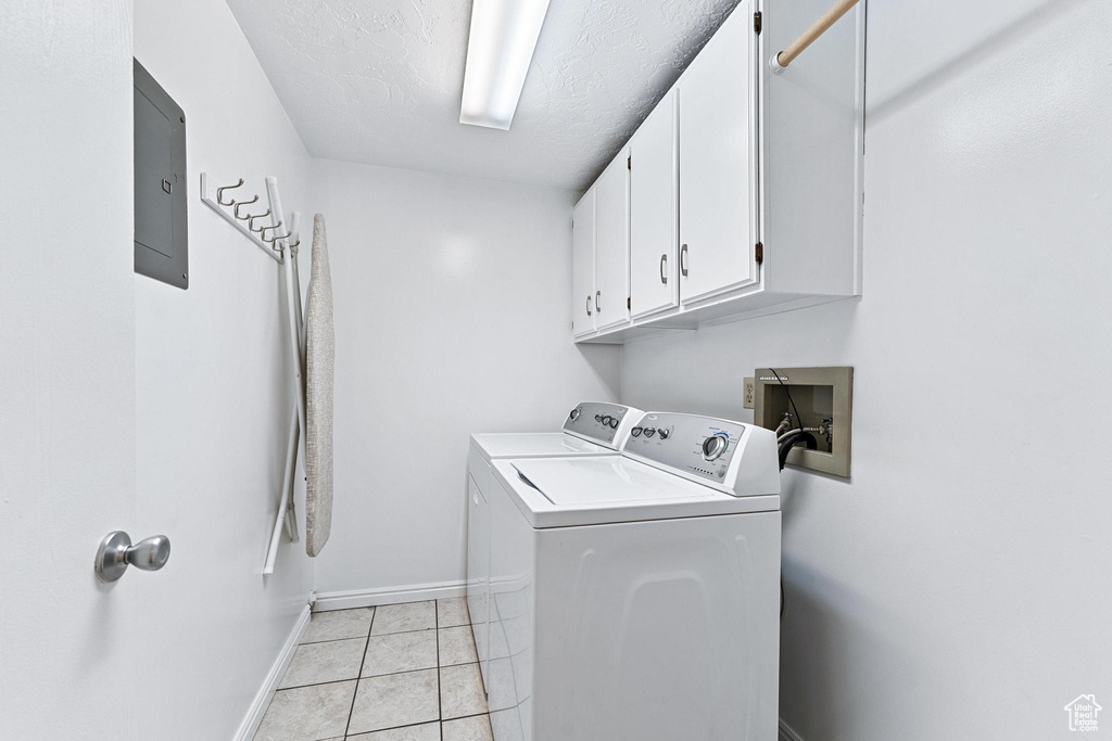 Clothes washing area featuring cabinets, independent washer and dryer, light tile flooring, and hookup for a washing machine