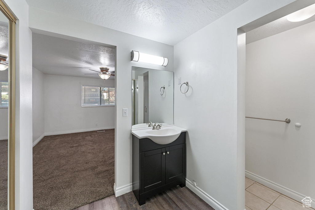 Bathroom with large vanity, tile floors, ceiling fan, and a textured ceiling