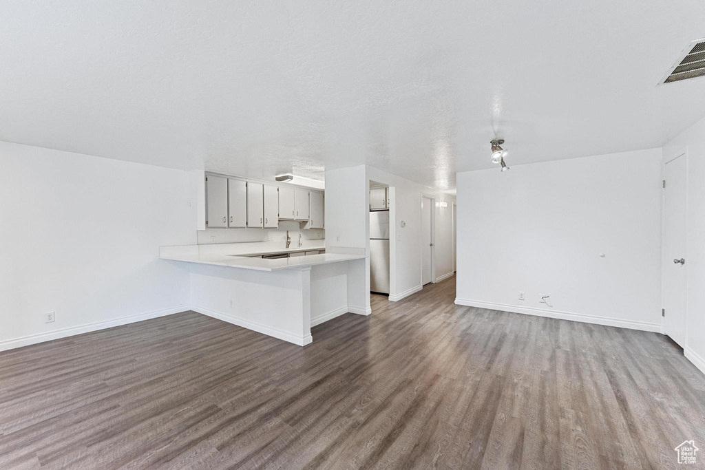 Kitchen featuring hardwood / wood-style flooring, kitchen peninsula, and stainless steel refrigerator