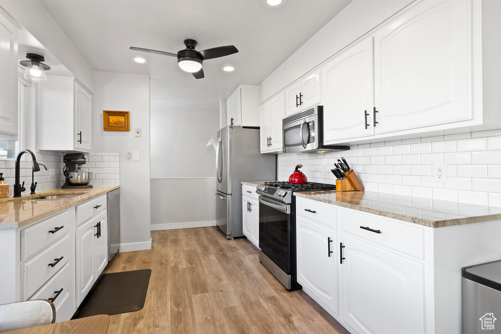 Kitchen featuring white cabinetry, ceiling fan, appliances with stainless steel finishes, and light wood-type flooring