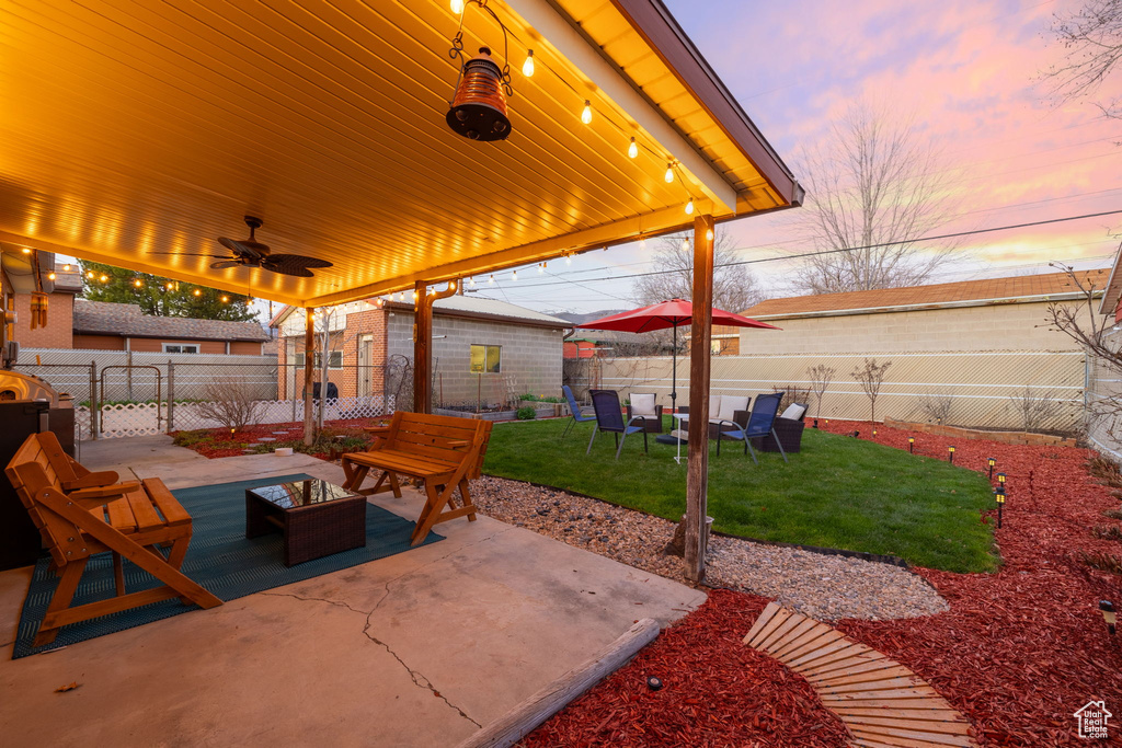Patio terrace at dusk with a lawn and ceiling fan