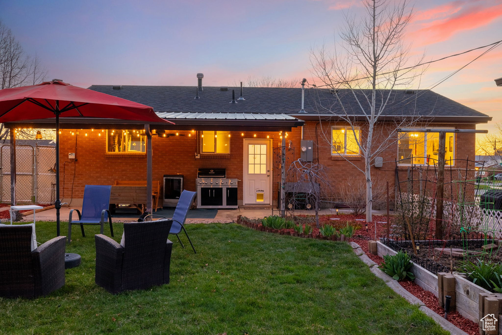 Back house at dusk with an outdoor hangout area, a patio, and a yard