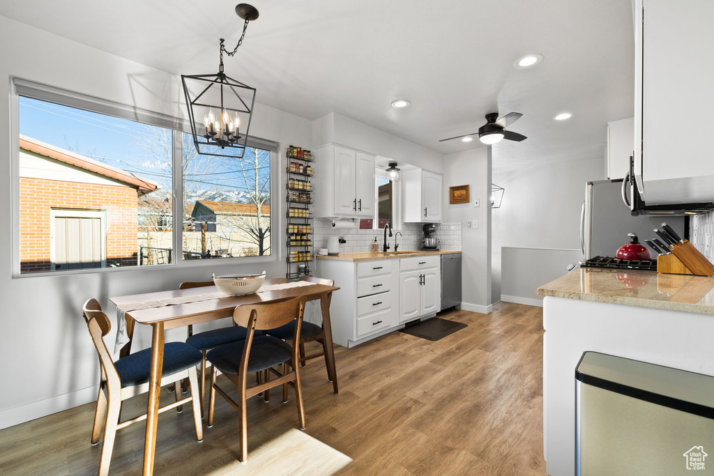 Kitchen featuring white cabinets, hanging light fixtures, tasteful backsplash, and light hardwood / wood-style floors