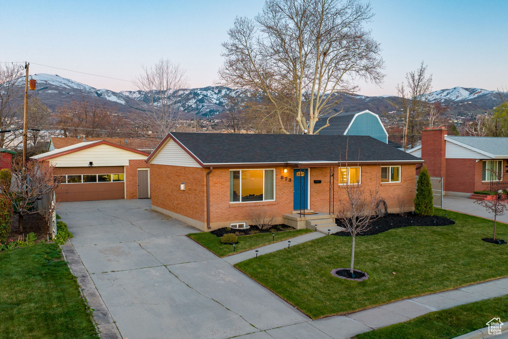 Single story home with a lawn, a mountain view, and a garage
