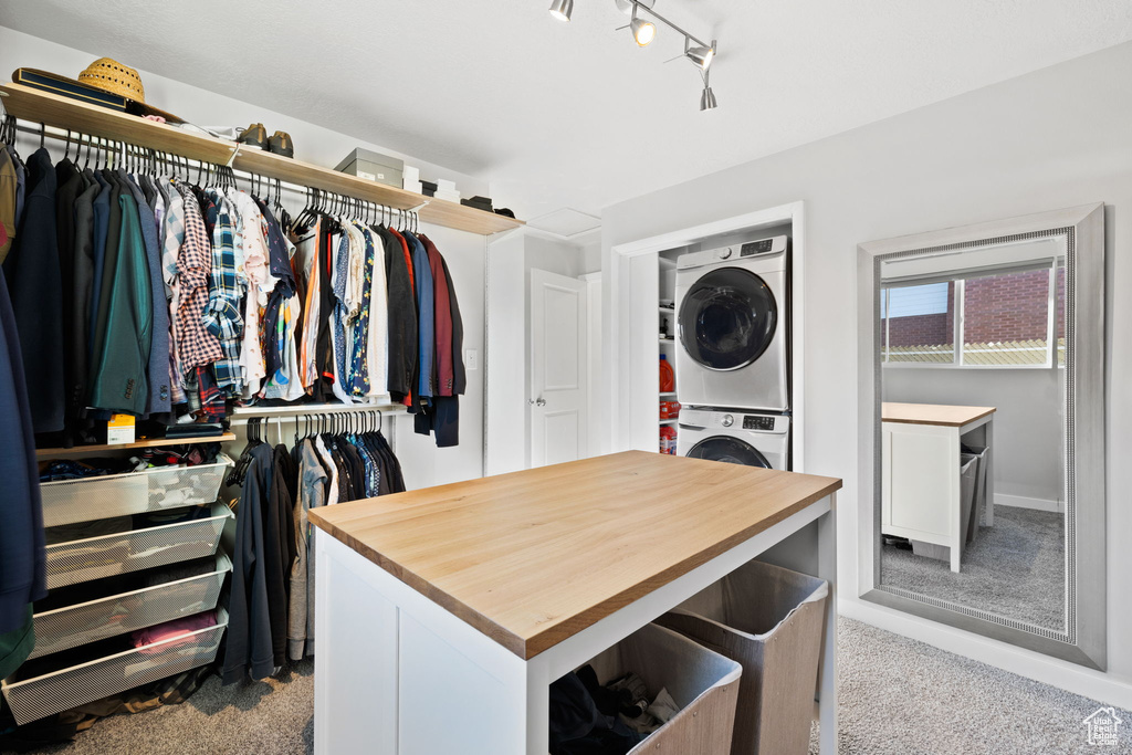 Spacious closet with light carpet and stacked washer / dryer