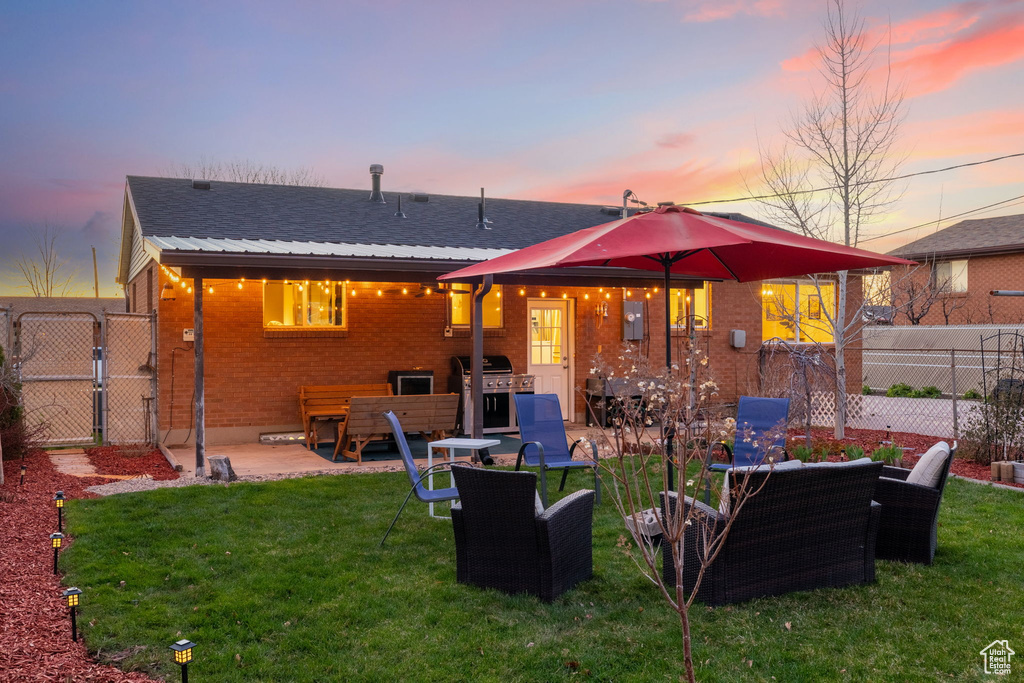 Back house at dusk featuring a lawn, an outdoor hangout area, and a patio area