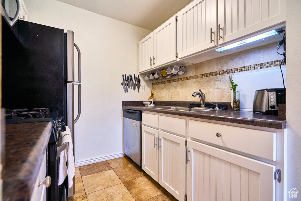 Kitchen featuring sink, stove, white cabinets, dishwasher, and backsplash