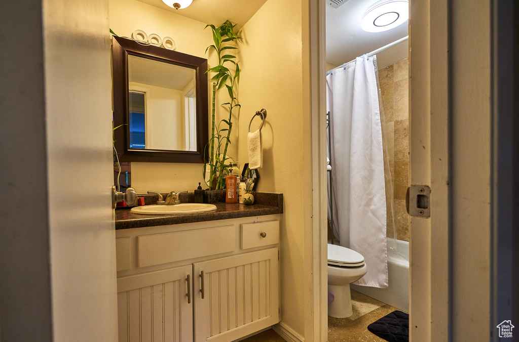 Full bathroom featuring oversized vanity, toilet, and shower / bathtub combination with curtain