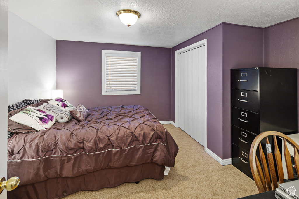 Bedroom featuring a closet, a textured ceiling, and light colored carpet