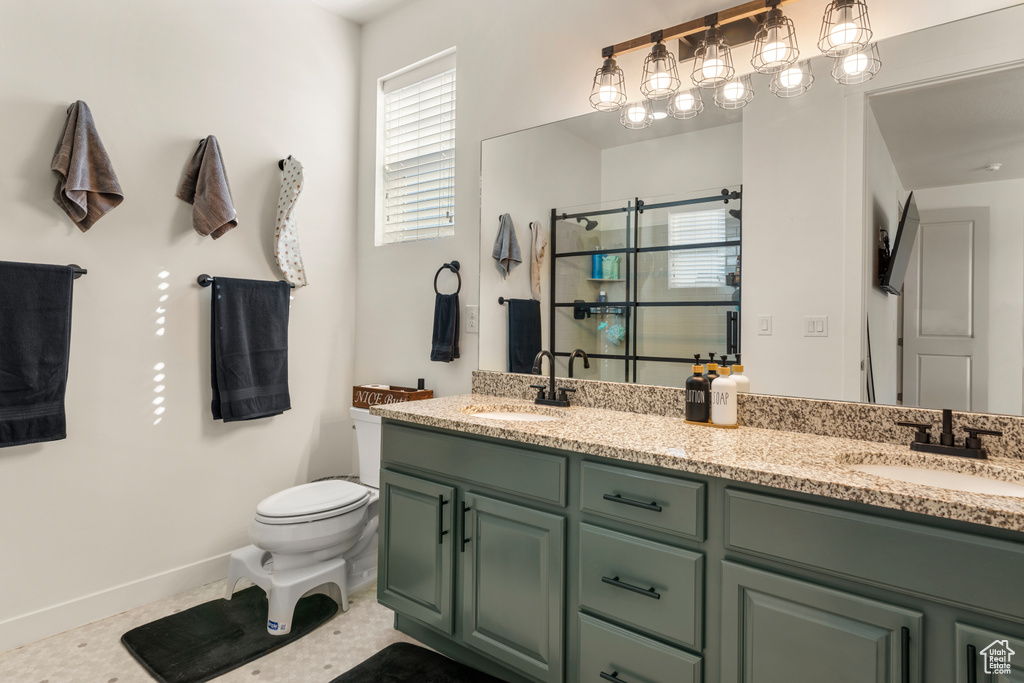 Bathroom featuring dual sinks, tile floors, toilet, and vanity with extensive cabinet space