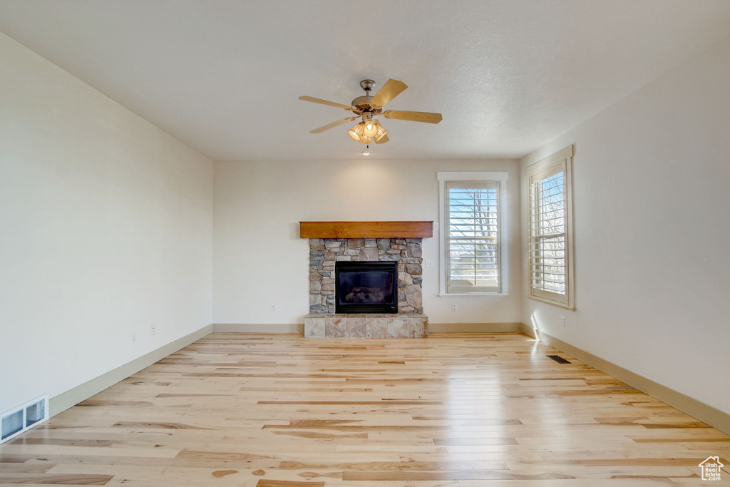 Unfurnished living room with ceiling fan, light wood-type flooring, and a fireplace