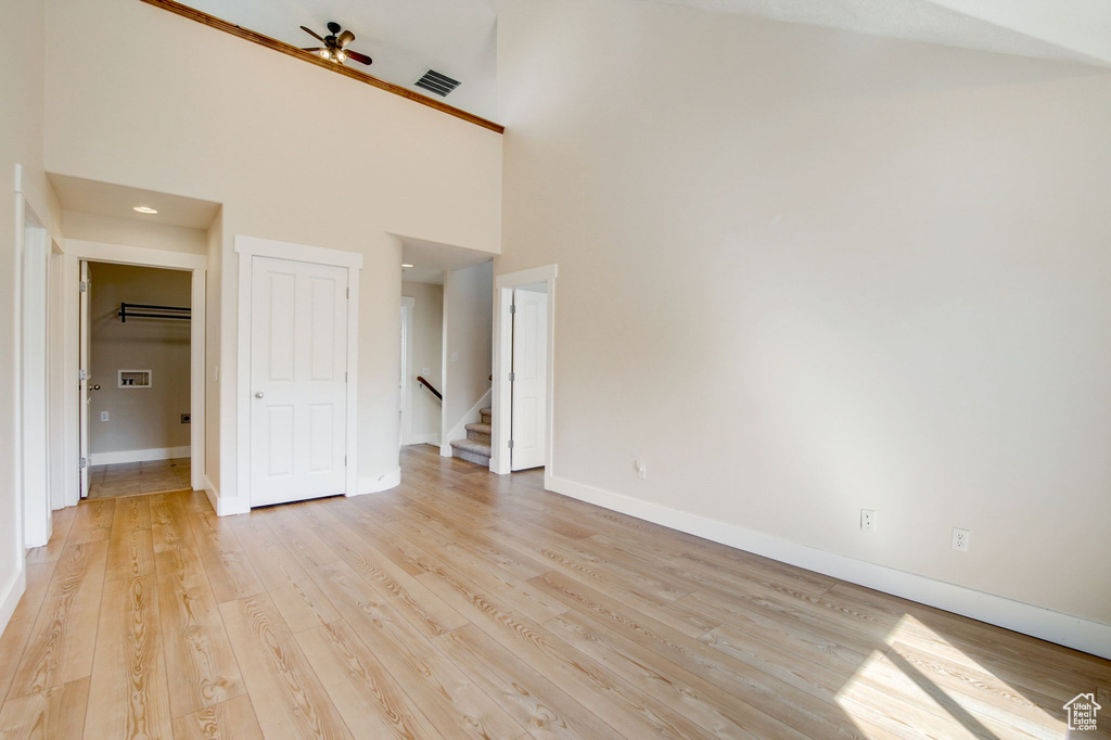 Unfurnished bedroom featuring light hardwood / wood-style floors and a towering ceiling