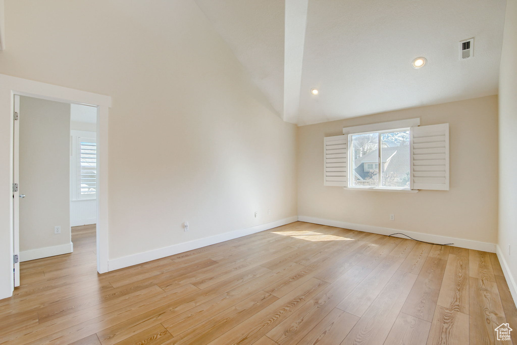 Empty room featuring high vaulted ceiling and light hardwood / wood-style flooring