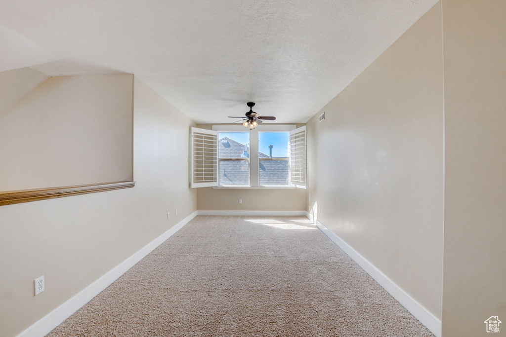 Carpeted empty room with a textured ceiling and ceiling fan