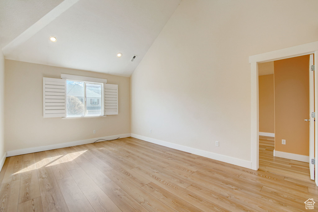 Spare room with high vaulted ceiling and light hardwood / wood-style flooring