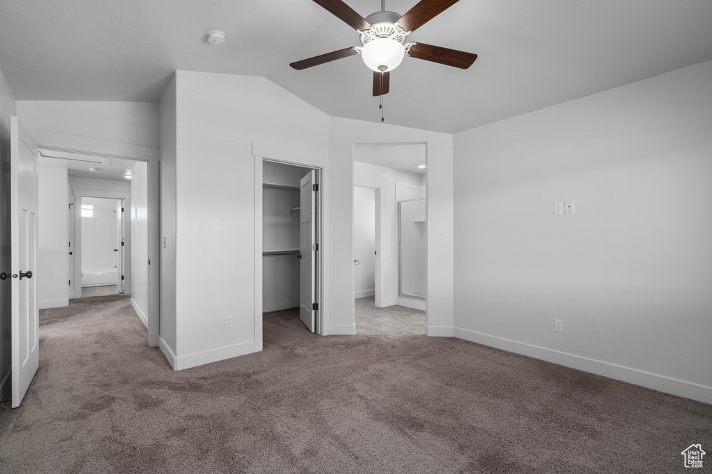 Unfurnished bedroom featuring ceiling fan, a walk in closet, vaulted ceiling, light carpet, and a closet