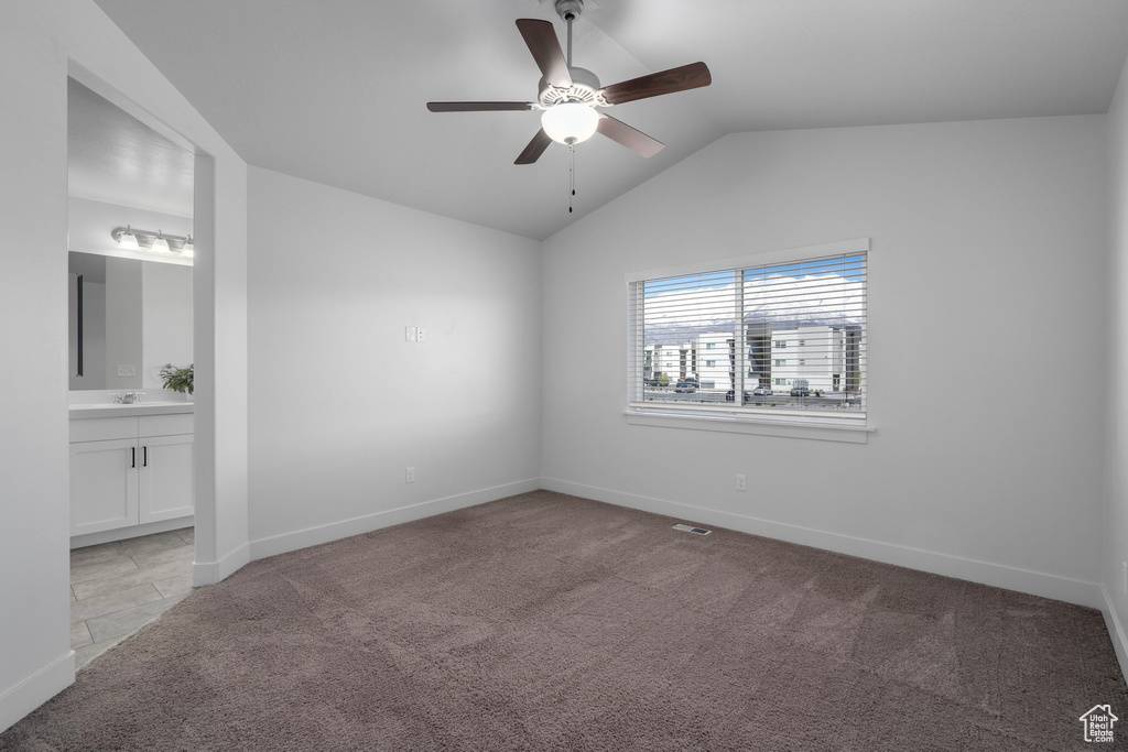 Carpeted spare room with sink, ceiling fan, and vaulted ceiling