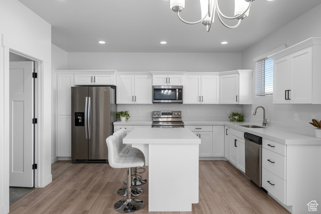 Kitchen featuring a center island, white cabinets, appliances with stainless steel finishes, and light wood-type flooring