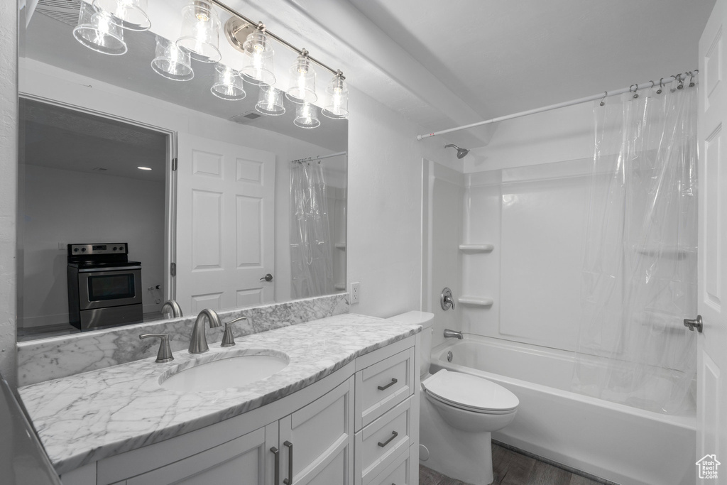 Full bathroom featuring shower / bath combo, oversized vanity, toilet, and wood-type flooring