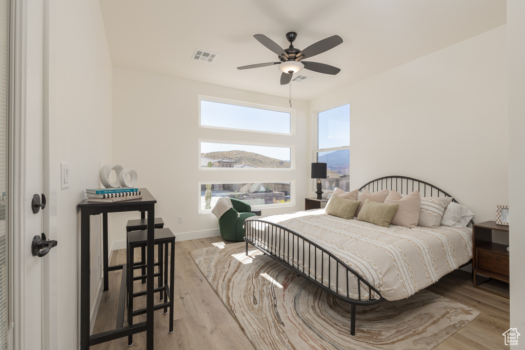 Bedroom featuring hardwood / wood-style flooring, multiple windows, and ceiling fan