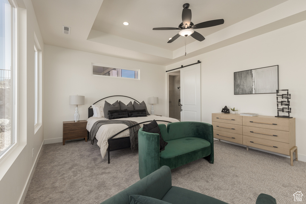 Carpeted bedroom with ceiling fan, a tray ceiling, and a barn door