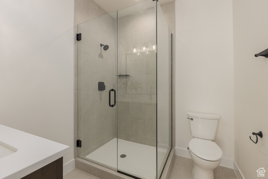 Bathroom featuring tile patterned floors, toilet, vanity, and an enclosed shower