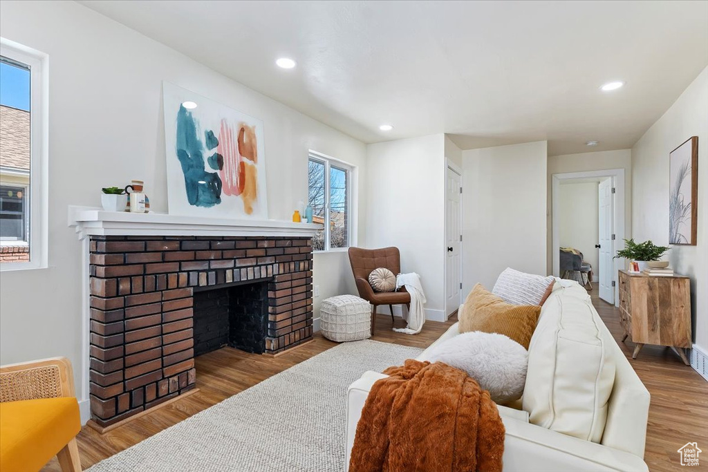 Living room with light hardwood / wood-style floors and a brick fireplace