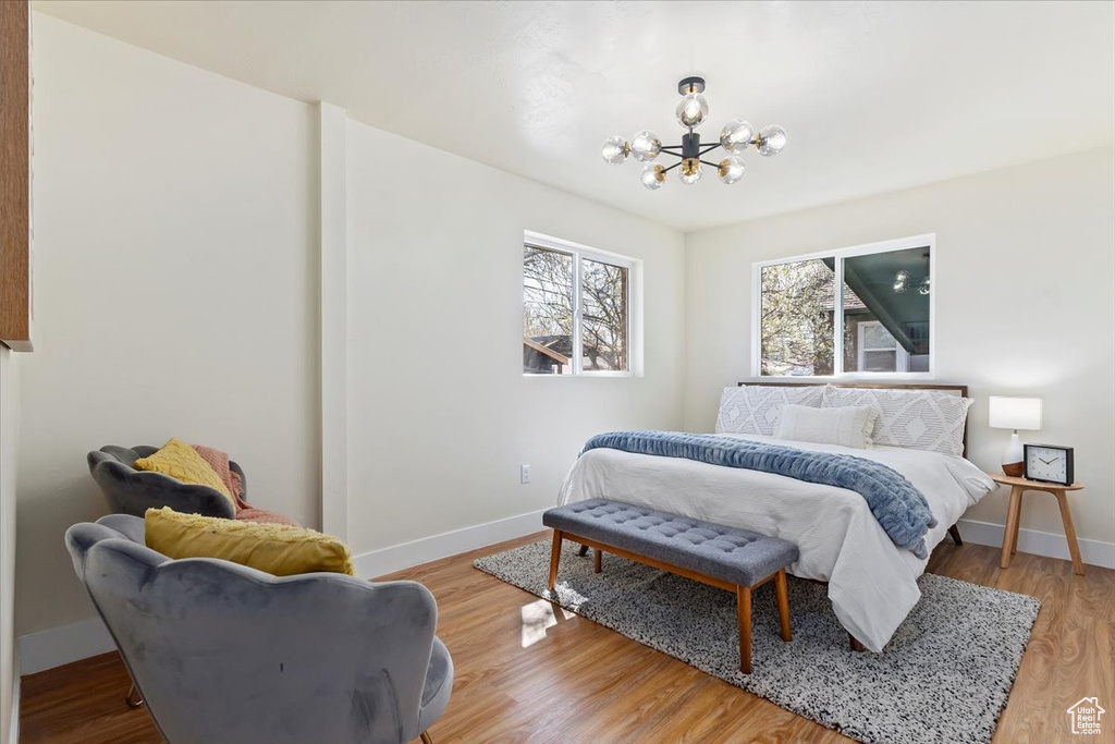 Bedroom with light hardwood / wood-style floors and a notable chandelier