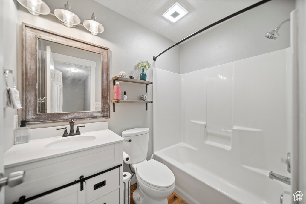 Full bathroom featuring a textured ceiling, shower / washtub combination, toilet, and vanity with extensive cabinet space