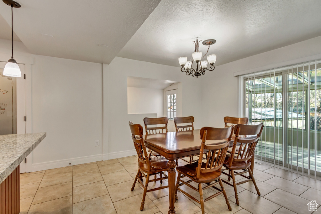Dining room with an inviting chandelier, a healthy amount of sunlight, and light tile floors