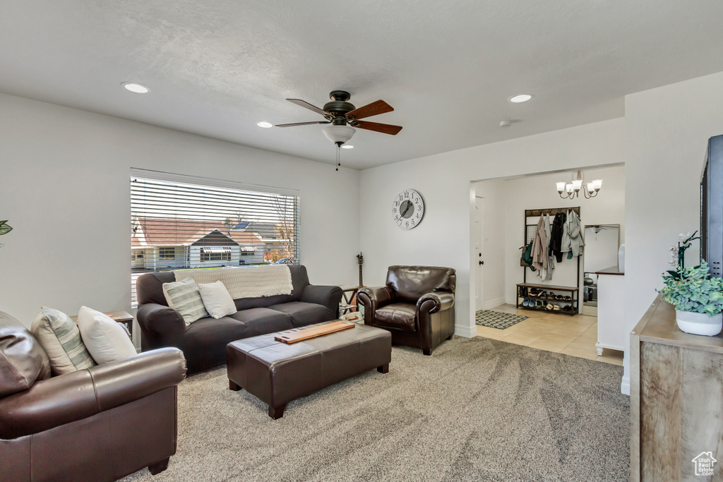 Carpeted living room featuring ceiling fan with notable chandelier