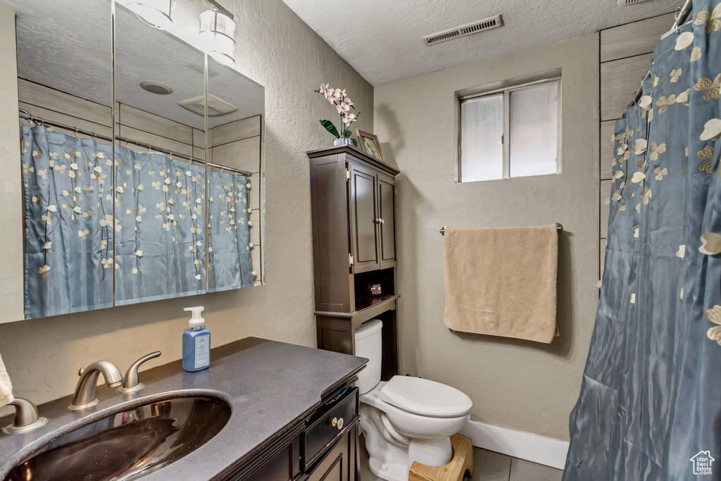 Bathroom featuring toilet, a textured ceiling, and vanity with extensive cabinet space