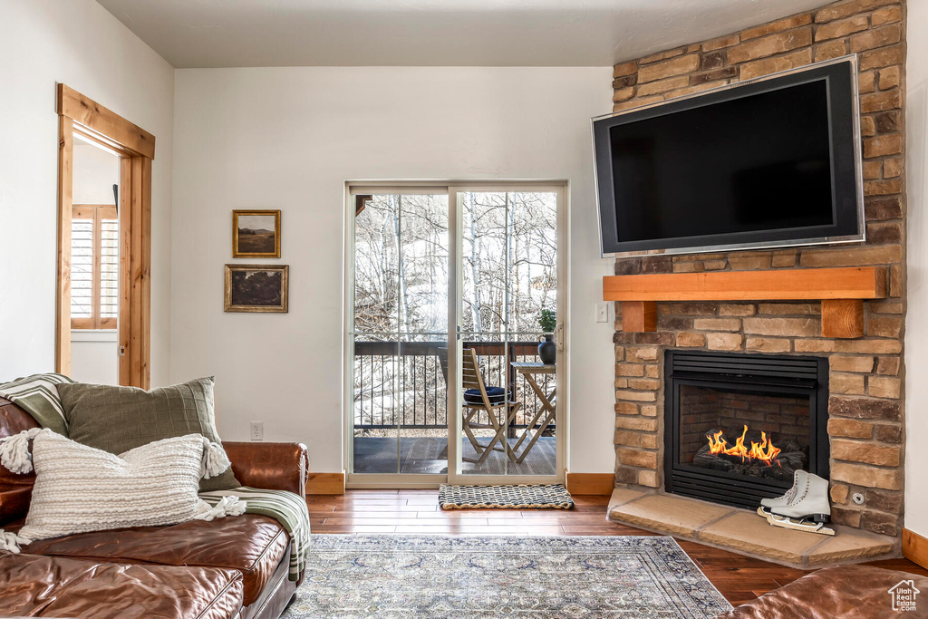 Living room featuring brick wall, a brick fireplace, and dark hardwood / wood-style flooring