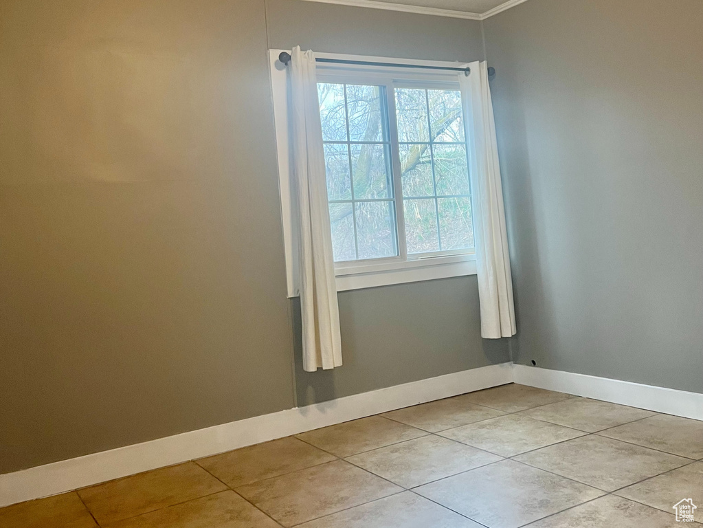 Spare room with crown molding, a textured ceiling, and light tile floors