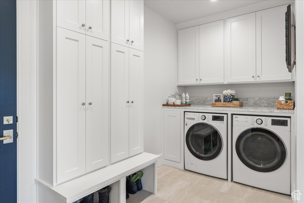 Laundry room with washer and clothes dryer, cabinets, and light hardwood / wood-style flooring