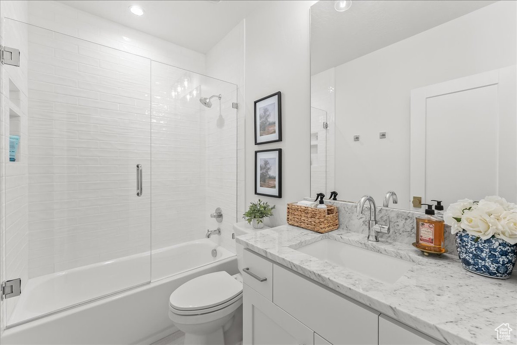 Full bathroom featuring toilet, shower / bath combination with glass door, and vanity