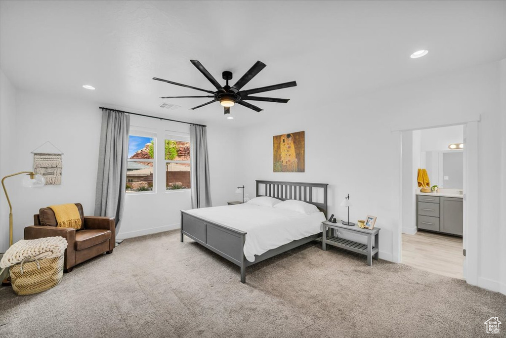 Bedroom with light carpet, ceiling fan, and ensuite bathroom